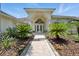 Beautiful home entrance features decorative glass double doors and lush tropical landscaping along a brick walkway at 19 Tomoka Cove Way, Ormond Beach, FL 32174