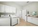 A spacious laundry room with white cabinets, sink, and modern washer and dryer units at 19 Tomoka Cove Way, Ormond Beach, FL 32174
