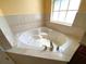 Corner soaking tub featuring tile accents and natural light at 19320 Oberly Pkwy, Orlando, FL 32833