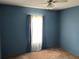 A bedroom with blue walls, a ceiling fan and natural light from the window at 1973 S Old Mill Dr, Deltona, FL 32725