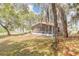 Spacious backyard featuring a screened-in lanai with chairs, mature trees, and lush greenery at 198 Heather Lane Dr, Deltona, FL 32738