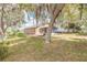 Spacious backyard featuring a screened-in lanai with chairs, mature trees, and lush greenery at 198 Heather Lane Dr, Deltona, FL 32738