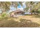 Spacious backyard featuring a screened-in lanai with chairs, mature trees, and lush greenery at 198 Heather Lane Dr, Deltona, FL 32738