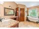 Elegant bathroom with a granite countertop, soaking tub, and a large window, offering a spa-like experience at 2 E Kelly Park Rd, Apopka, FL 32712
