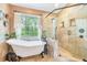 Bright bathroom featuring a clawfoot tub, glass shower, and a large window overlooking the yard at 2 E Kelly Park Rd, Apopka, FL 32712