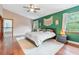 Large bedroom with wood floors, green accent wall, a ceiling fan, and two windows, creating a peaceful retreat at 2 E Kelly Park Rd, Apopka, FL 32712