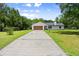 Modern home with long drive, wood garage door, and front lawn at 2455 Whooping Crane Dr, De Leon Springs, FL 32130