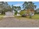 Exterior view showing two outbuildings, a shed and detached garage, next to the gravel drive and green lawn at 25305 Mardon Cir, Paisley, FL 32767