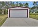 Exterior shot of a white garage with a red trim and concrete driveway at 25305 Mardon Cir, Paisley, FL 32767