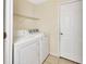 Functional laundry room with washer, dryer, utility shelf, and tile flooring at 28045 Poinsettia Ave, Paisley, FL 32767