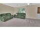 Cozy living room with carpeted floor and comfortable green sofas at 28045 Poinsettia Ave, Paisley, FL 32767
