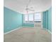 This empty blue bedroom offers carpet flooring, ceiling fan, and balcony access overlooking the ocean at 3051 S Atlantic Ave # 1003, Daytona Beach, FL 32118