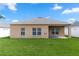 Well-maintained backyard with lush green grass and a neutral-colored single-story house with three windows and a covered patio at 452 Casa Marina Pl, Sanford, FL 32771