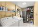 Well-lit laundry room with washer, dryer, refrigerator, and ample storage shelves at 4638 Saxon Dr, New Smyrna Beach, FL 32169