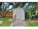 Backyard view of the white storage shed with accessibility ramp, surrounded by lawn and landscaping at 4791 S Peninsula Dr, Ponce Inlet, FL 32127