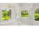 Bright bathroom featuring a soaking tub, glass shower with gold fixtures, and scenic views through large windows at 4885 State Road 11, De Leon Springs, FL 32130