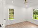 Bright bedroom featuring laminate floors, two windows, and a ceiling fan at 4885 State Road 11, De Leon Springs, FL 32130