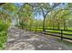 Picturesque driveway lined with a black fence and shaded by mature trees at 4885 State Road 11, De Leon Springs, FL 32130