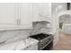 Modern kitchen featuring stainless steel gas range, marble countertops, and custom white cabinets at 4885 State Road 11, De Leon Springs, FL 32130