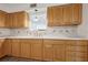 Bright kitchen with white countertops, wood cabinets, tile backsplash and a view to another room through the window at 510 Sandy Bluff Trl, Deland, FL 32724