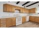 Kitchen featuring white appliances, wood cabinets, tile backsplash and decorative ceiling beams at 510 Sandy Bluff Trl, Deland, FL 32724