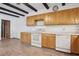 Kitchen featuring white appliances, wood cabinets, tile backsplash and decorative ceiling beams at 510 Sandy Bluff Trl, Deland, FL 32724