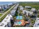 Aerial view of condos featuring tennis courts, a swimming pool, beautiful landscaping, parking, roadways, and scenic beachfront views at 5300 S Atlantic Ave # 12-401, New Smyrna Beach, FL 32169