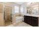 Bright bathroom featuring a soaking tub, glass shower, and dark wood vanity with stylish tile flooring at 565 Morgan Wood Dr, Deland, FL 32724