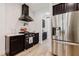 Modern kitchen featuring dark cabinetry, a sleek range hood, and stainless steel refrigerator at 565 Morgan Wood Dr, Deland, FL 32724