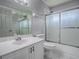 Well-lit bathroom features a sleek white vanity, tiled floors, and a shower with glass doors at 5936 Boggs Ford Rd, Port Orange, FL 32127