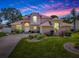 A beautiful two-story home with brick accents, manicured lawn, and a vibrant sunset sky as backdrop at 5936 Boggs Ford Rd, Port Orange, FL 32127