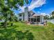 Beautiful home exterior featuring a well-manicured lawn, mature trees, a covered patio, and a spacious backyard, great for outdoor living at 5936 Boggs Ford Rd, Port Orange, FL 32127
