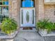 Elegant front door with decorative glass, brick surround, and potted plants creating a welcoming entrance to the home at 5936 Boggs Ford Rd, Port Orange, FL 32127