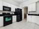 Modern kitchen equipped with black appliances, white cabinetry, and a tiled floor offers a clean and efficient cooking space at 5936 Boggs Ford Rd, Port Orange, FL 32127