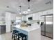 Modern white kitchen featuring stainless steel appliances, quartz countertops, and a stylish island with seating at 28432 Tammi Dr, Tavares, FL 32778