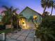 Charming home exterior with a two-car garage, tropical landscaping, and a well-lit front porch at 3110 John Anderson Dr, Ormond Beach, FL 32176