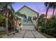 Charming home exterior with a two-car garage, tropical landscaping, and a well-lit front porch at 3110 John Anderson Dr, Ormond Beach, FL 32176