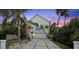 Charming home exterior with a two-car garage, tropical landscaping, and a well-lit front porch at 3110 John Anderson Dr, Ormond Beach, FL 32176