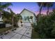 Charming home exterior with a two-car garage, tropical landscaping, and a well-lit front porch at 3110 John Anderson Dr, Ormond Beach, FL 32176
