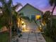 Charming home exterior with a two-car garage, tropical landscaping, and a well-lit front porch at 3110 John Anderson Dr, Ormond Beach, FL 32176