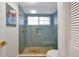 Modern shower with blue tiling, gold fixtures, glass door, and practical built-in storage niche at 3988 Radley Ct, Longwood, FL 32779