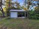Features an outbuilding with garage door, carport, and metal roof on a partially wooded lot at 2719 Brookline Ave, New Smyrna Beach, FL 32168