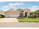 Tan one-story house with three car garage, and landscaped yard at 5631 Superior Dr, Lakeland, FL 33805