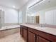 Bathroom featuring double sink vanity, large mirror, tub, shower, and tile flooring at 2588 Egret Loop, Kissimmee, FL 34743