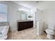 Bathroom featuring dual sinks, large mirrors, tile floors, tub, shower and toilet at 2588 Egret Loop, Kissimmee, FL 34743