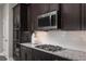 Close-up of kitchen with stainless steel microwave, granite countertops, and dark wood cabinets at 3786 Sky Mountain Aly, Apopka, FL 32712