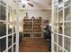 This is a well-organized home office featuring a large bookshelf and hardwood floors, as seen through glass panel doors at 8320 Sw 82Nd Loop, Ocala, FL 34481