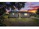 Charming single-story home with white brick and a covered carport set against a vibrant sunset backdrop at 5030 Alderman Rd, Lakeland, FL 33810