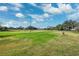 Spacious green yard with scattered trees under a beautiful blue sky and fluffy clouds at 5030 Alderman Rd, Lakeland, FL 33810