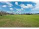 Large, green lawn under a partly cloudy sky with a few trees in the distance at 5030 Alderman Rd, Lakeland, FL 33810